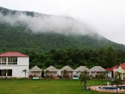 Resort cottages with red roofs at Garh Panchkot, Purulia, surrounded by green hills and misty clouds.